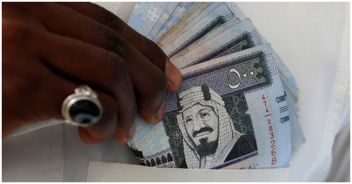 সৌদি রিয়াল হাতে এক ব্যক্তি। ছবি: রয়টার্স